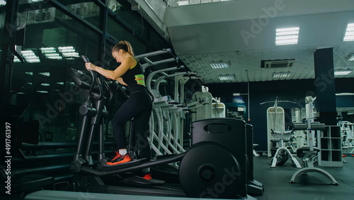 Fit Athletic Woman Exercising on an Elliptical Machine. Muscular Women Activity Training in Modern Gym. Sports People Workout in an Elliptic Walking Trainer Fitness. Exercise Slow Motion