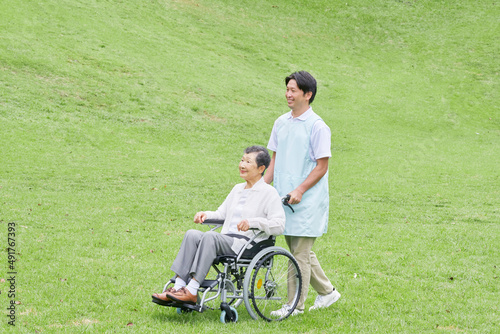 車椅子に乗った高齢者と介護士 屋外