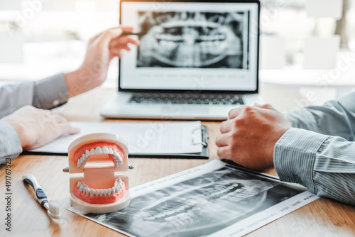 Dentist with male patient presenting discussing dental problems x-ray image film in dental office photo