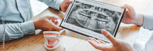 Dentist with male patient presenting discussing dental problems x-ray image film in dental office photo