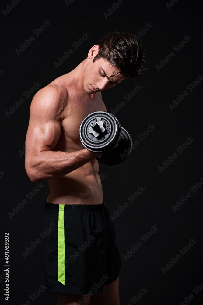 One more. Studio shot of a young man working with dumbbells isolated on black. One more. Studio shot of a young man working with dumbbells isolated on black.