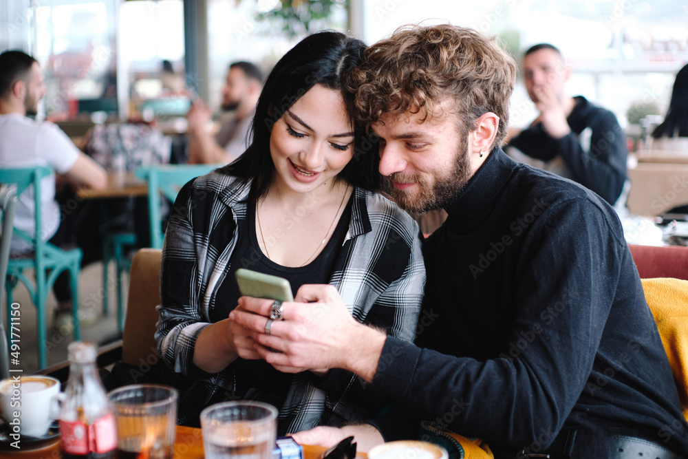 couple in a cafe looking phone and smiles