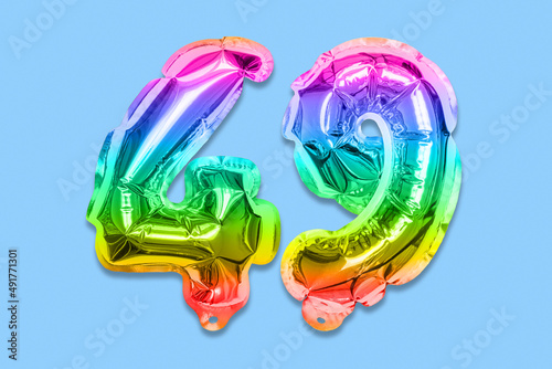 Rainbow foil balloon number, digit forty nine on a blue background. Birthday greeting card with inscription 49. Top view. Numerical digit. Celebration event, template. photo