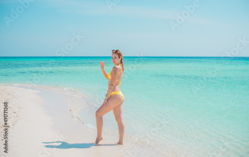 Ukrainian woman in yellow swimsuit in vacation, behind blue landscape, fashionable details