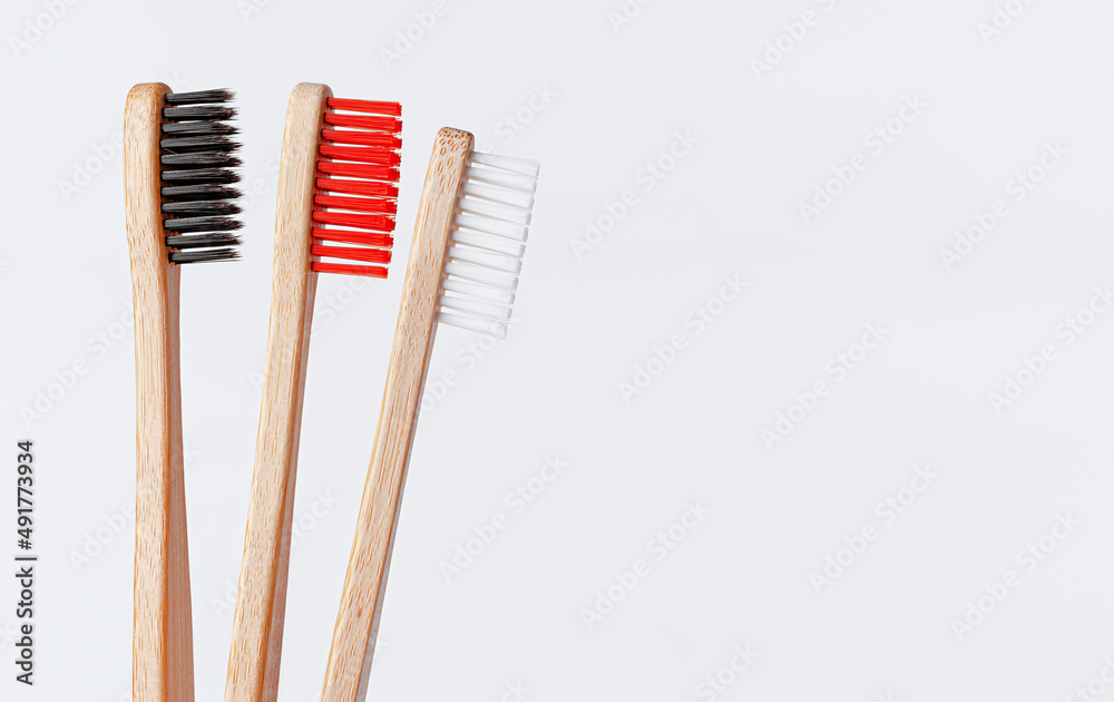Red, white and black bamboo toothbrushes on white background. Copy space, close up. Red, white and black bamboo toothbrushes on white background. Copy space, close up.