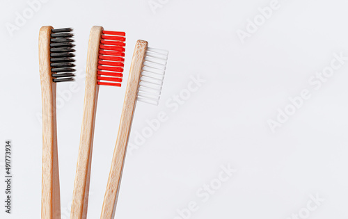 Red, white and black bamboo toothbrushes on white background. Copy space, close up.