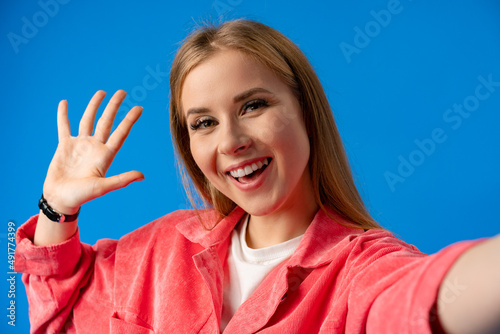 Happy woman taking selfie against studio color background