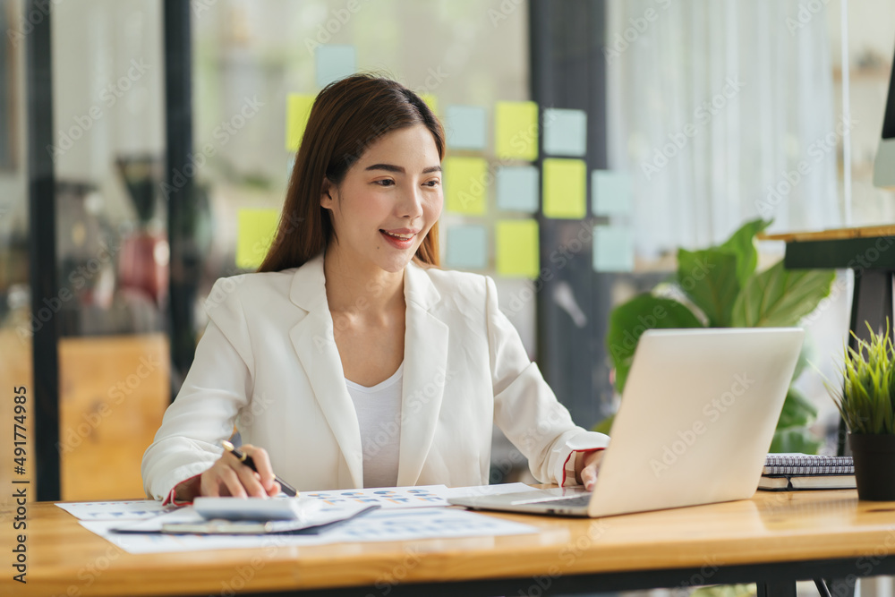 Asian young beautiful joyful woman smiling while working with laptop in office. Asian young beautiful joyful woman smiling while working with laptop in office.