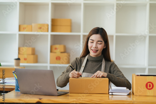 Starting Small business entrepreneur SME freelance,Portrait young woman working at home office, BOX,smartphone,laptop, online, marketing, packaging, delivery, SME, e-commerce concept © PaeGAG