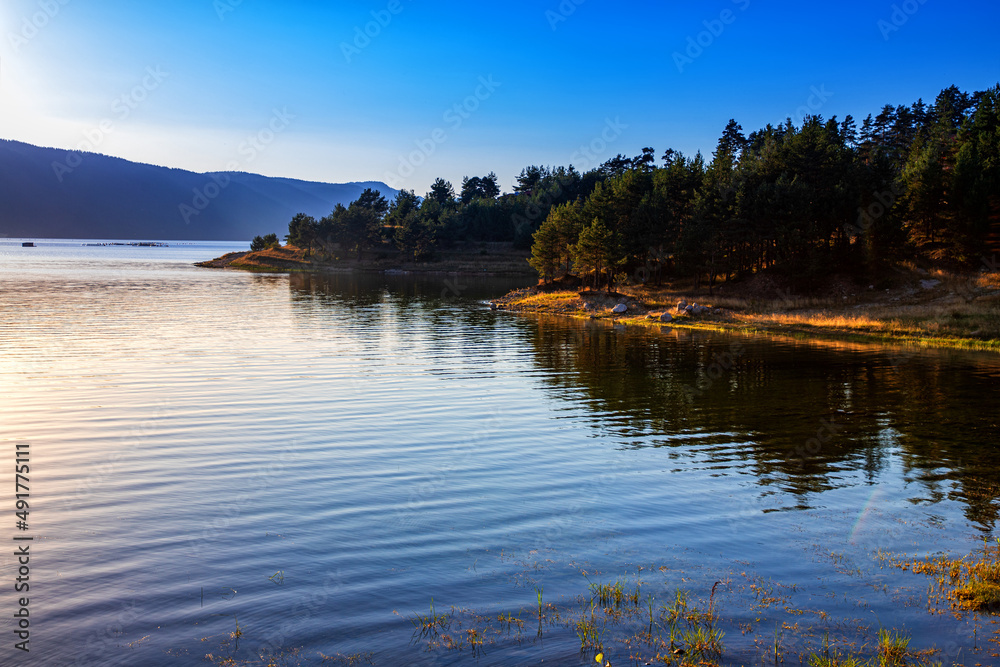 Obraz premium Idyllic mountain landscape at lake with calm water, tree reflection after sunset