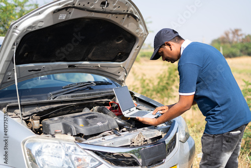 professional mechanic using laptop for checking car by lifting car hood on highway road - concept of technology, mobile repair service and support.