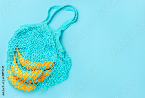 Reusable string bag with bananas on blue background. Zero waste and eco lifestyle concept. Copy space