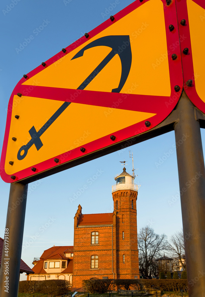 Lighthouse in Ustka on the background of the prohibitory sign of anchoring at sunset. Pomerania, Poland.
