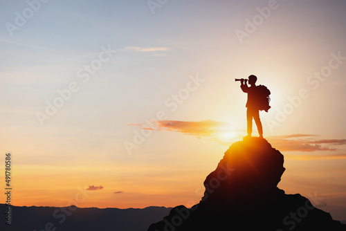 vision for success ideas. businessman's perspective for future planning. Silhouette of man holding binoculars on mountain peak against bright sunlight sky background. photo