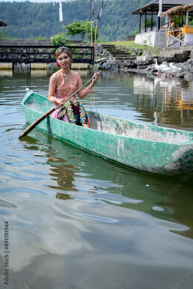 Young girl paddling on a wooden canoe in traditional clothes, and Hindu