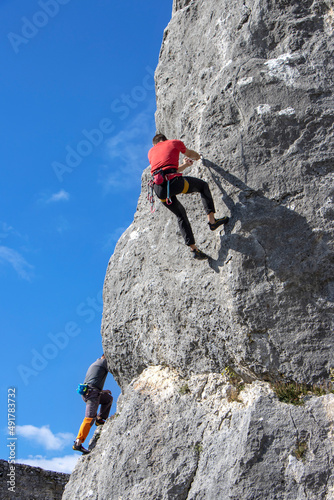 Two young male climber climbs on a cliff