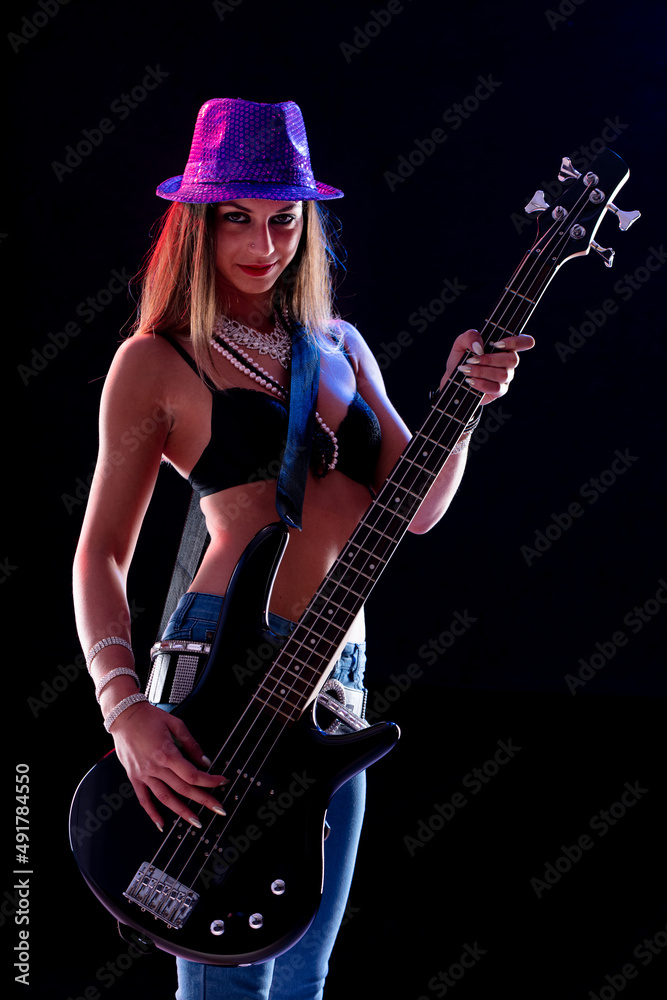 Sexy young female guitarist in chic trendy outfit on stage