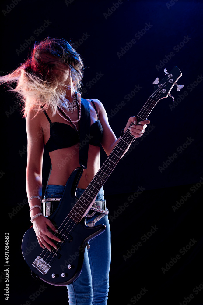 Hipster young female guitarist performing on stage