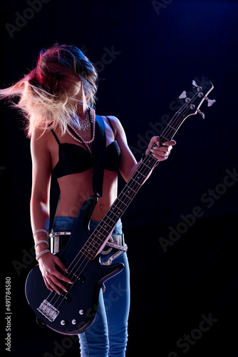 Hipster young female guitarist performing on stage