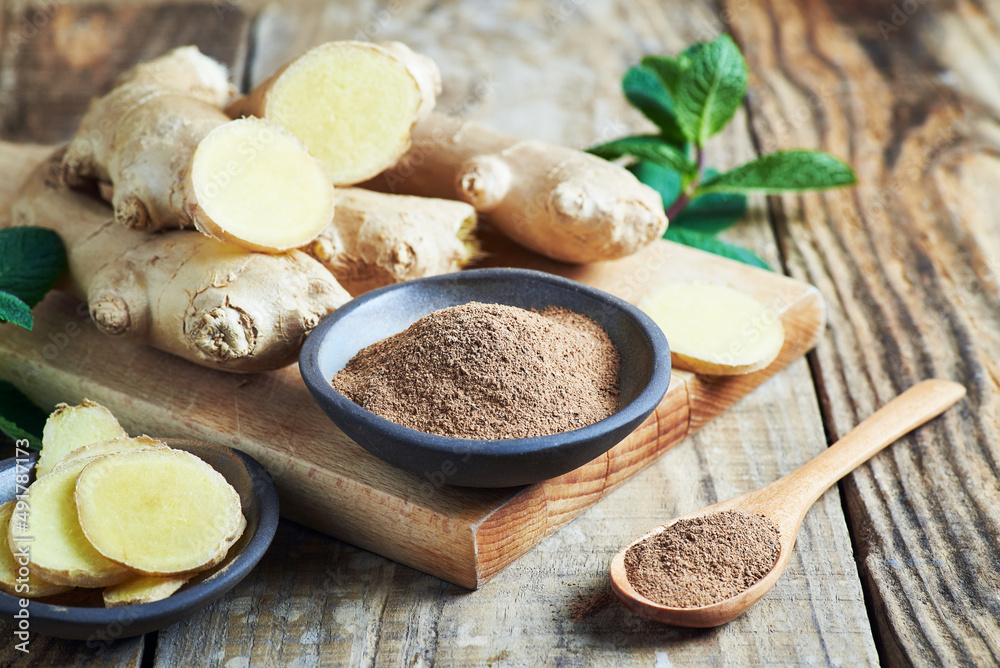 Fototapeta premium Ginger root and grounded ginger powder. Fresh ginger root and grounded ginger powder served on wooden table.