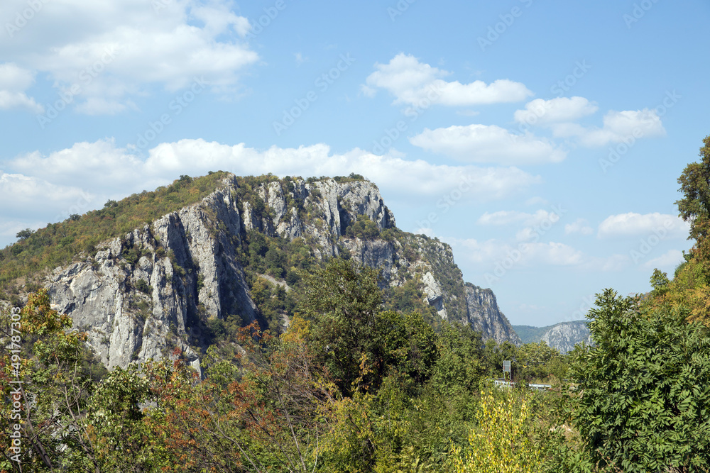Top of the rocky mountain Djerdap National Park,  Serbia. Djerdapska klisura. Carpathian Mountains. Clear blue sky with white clouds over the mountain.Copy space, postcard, greeting card.