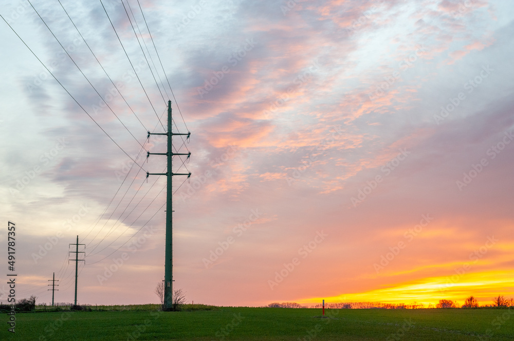 Obraz premium The setting sun in the flemish country side colors the sky intensely yellow and orange.