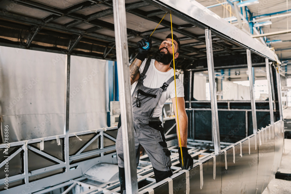 An auto mechanic measuring new bus at mechanic shop. An auto mechanic measuring new bus at mechanic shop.