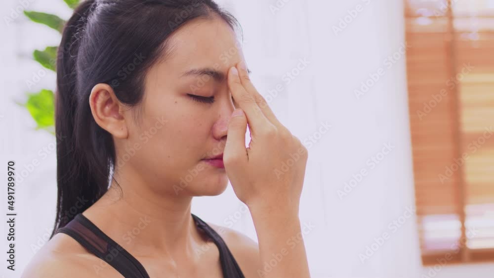 To guide her breath, an Asian lady touches her forehead with her fingers. To get started with yoga and meditation To guide her breath, an Asian lady touches her forehead with her fingers. To get started with yoga and meditation