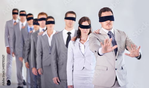 Blind leadership. A row of blindfolded businesspeople following a blindfolded leader. photo