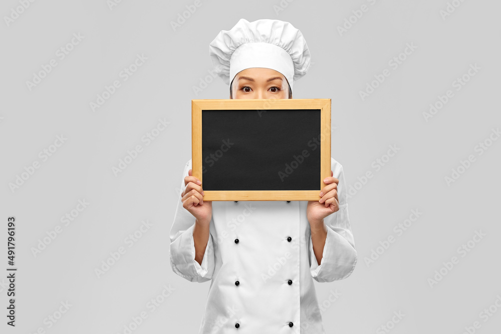 cooking, advertisement and people concept - female chef holding black chalkboard over grey background cooking, advertisement and people concept - female chef holding black chalkboard over grey background