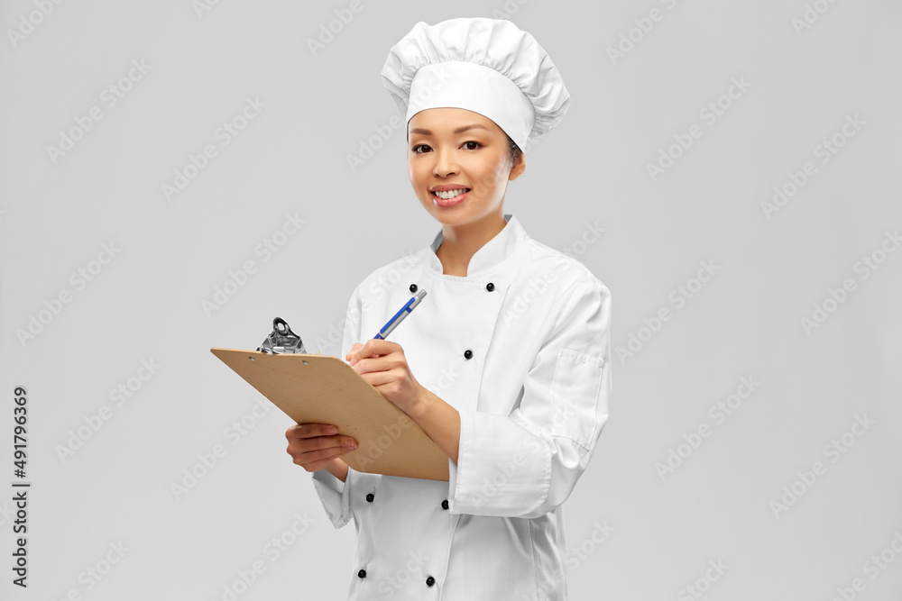 cooking, culinary and people concept - happy smiling female chef with clipboard and pen over grey background cooking, culinary and people concept - happy smiling female chef with clipboard and pen over grey background