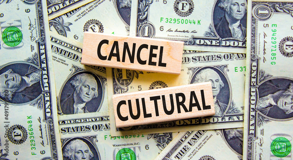 Cancel cultural symbol. Concept words Cancel cultural on wooden blocks on a beautiful background from dollar bills. Business and cancel cultural concept, copy space.