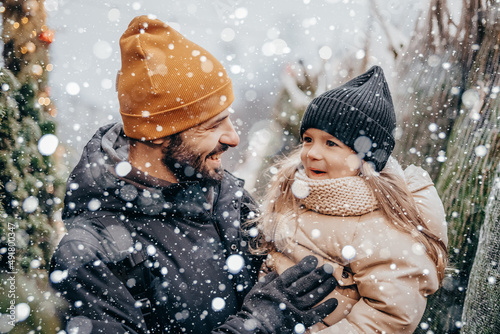 Winter holidays and people concept - happy father and little daughter choosing christmas tree at street market. Choosing and buying a Christmas tree at the Christmas market