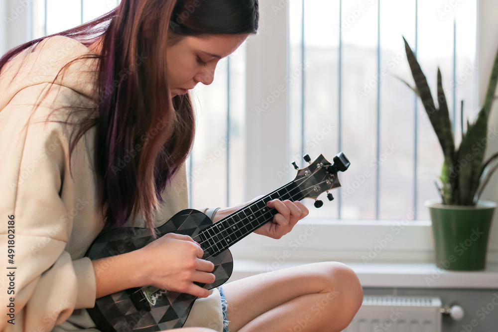 custom made wallpaper toronto digitalA young woman learns a new hobby, learns to play the ukulele at home