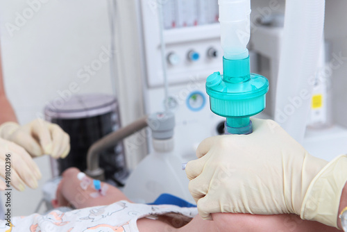The resuscitator holds an oxygen mask on the child s face. The face is out of focus.Surgery under general anesthesia. A device for artificial lung ventilation. Oxygen mask.Photo in the operating room.