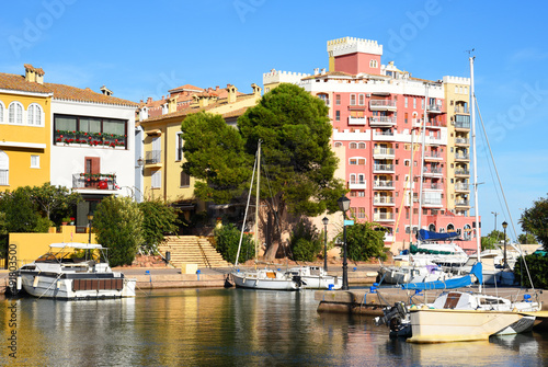 Yachts and motor boats in marina Port Saplaya, Valencia, Alboraya, Spain. Luxury yacht and fishing motorboat in yacht club on background of the colourful houses at Mediterranean Sea. Sailboat port. photo