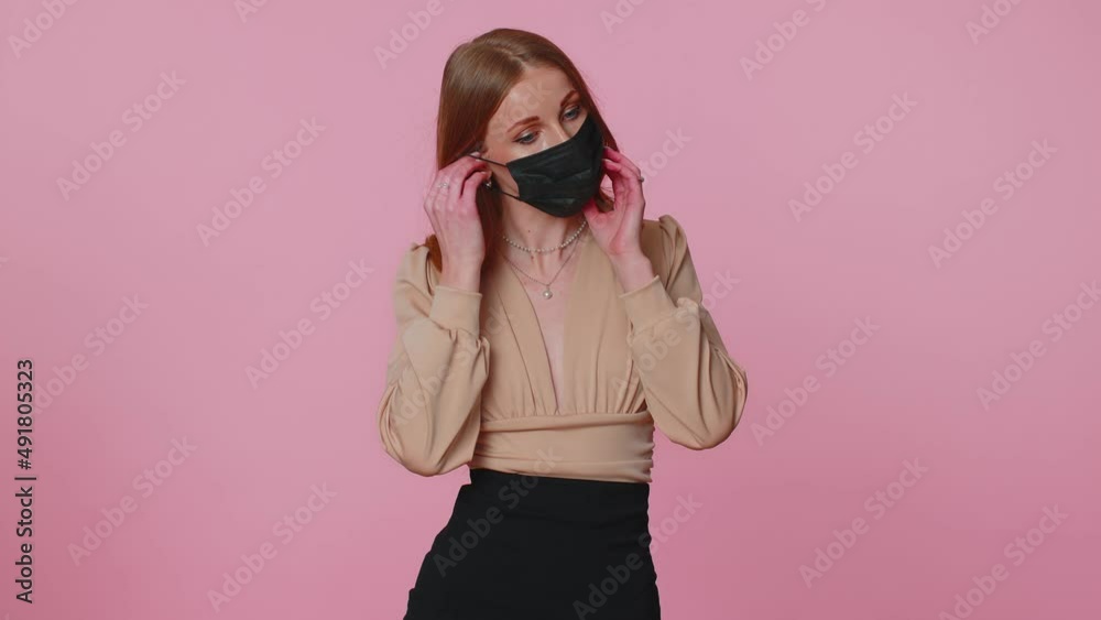 Sad unhappy girl putting on face hygienic medical mask to prevent respiratory infection, airborne epidemic flu disease, contagious Coronavirus Covid-19. Indoors studio shot isolated on pink background Sad unhappy girl putting on face hygienic medical mask to prevent respiratory infection, airborne epidemic flu disease, contagious Coronavirus Covid-19. Indoors studio shot isolated on pink background