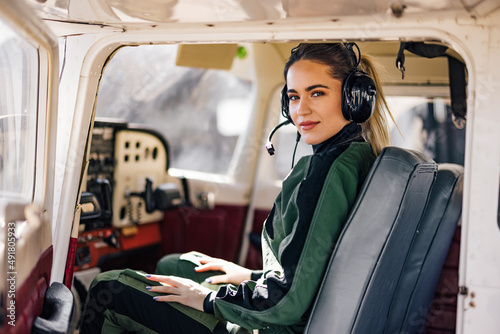 Billede på lærred Portrait of the happy copilot, sitting in the cockpit, wearing aircraft headphones