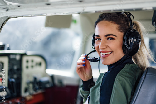 Confident female plane captain, ajusting her microphone, prepari