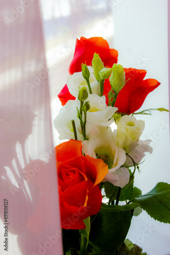 bouquet of white and orange spring roses on a soft pink background