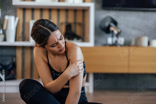 Young sports girl, holding arm, having an injury.