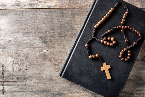 Rosary catholic cross on holy bible on wooden table. Top view. Copy space photo