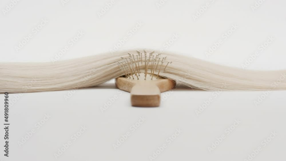 Rig shot of Lock of blonde hair on brush comb on grey background | Hair care concept