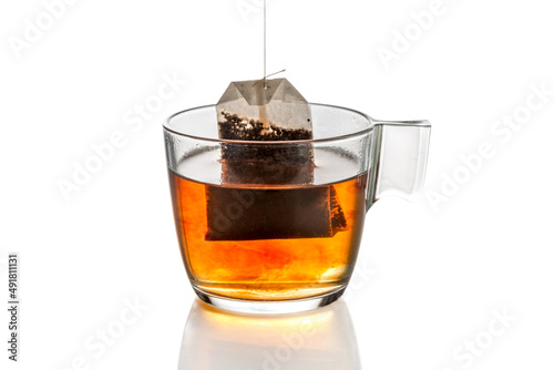 Infused tea bag creates tea in hot water in the clear glass cup isolated on white, clipping path