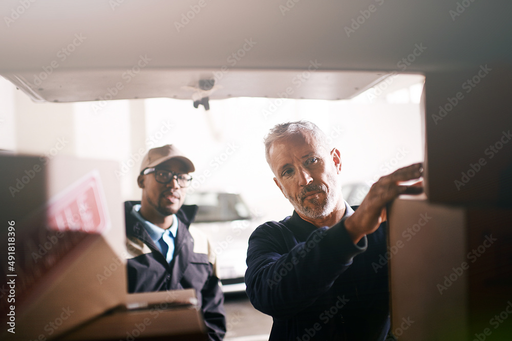 Loading your goods with the utmost care. Shot of delivery men loading ...
