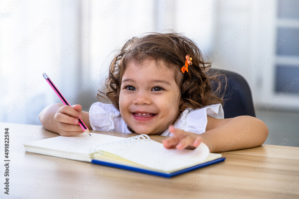 Cute young preschool Caucasian child girl drawing with pencil at desk Cute young preschool Caucasian child girl drawing with pencil at desk