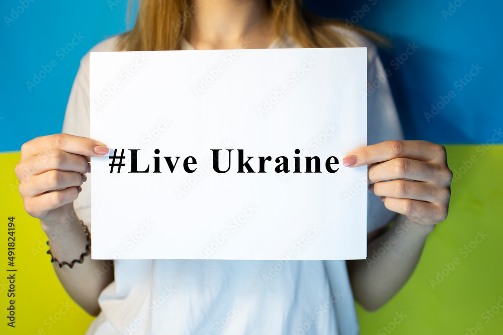 Girl holding a sign protesting war raises banner with inscription Stop War at blue yellow flag of country Ukraine. Call to stop war, crisis in Ukraine. Girl holding a sign protesting war raises banner with inscription Stop War at blue yellow flag of country Ukraine. Call to stop war, crisis in Ukraine.
