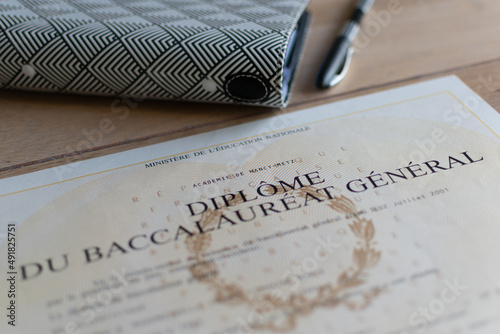 Baccalaureate : close up of a french diploma with some books, the text means general baccalaureate diploma photo