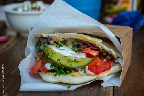 Fototapeta Naklejka Na Ścianę i Meble -  Israeli style Chickpea falafel in pita bread with  hummus, red cabbage, tomato, onion, pickled and fresh cucumber, tahini, arisa and greens served in Saint Petersburg, Russia
