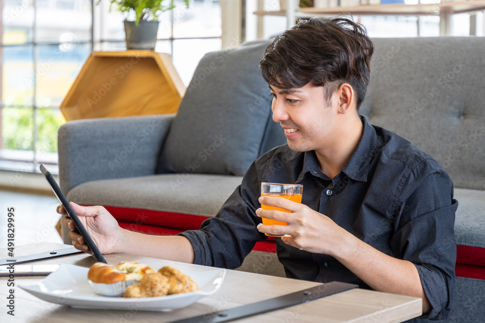 Asian businessman freelance sitting on floor front of sofa using table with meal breakfast. Concept for working at home. Asian businessman freelance sitting on floor front of sofa using table with meal breakfast. Concept for working at home.